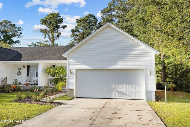 exterior space featuring a porch, a garage, and a front yard