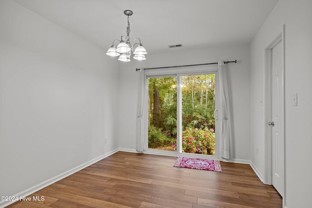 unfurnished dining area featuring a chandelier and wood-type flooring