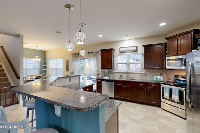 kitchen with sink, hanging light fixtures, a notable chandelier, a spacious island, and appliances with stainless steel finishes