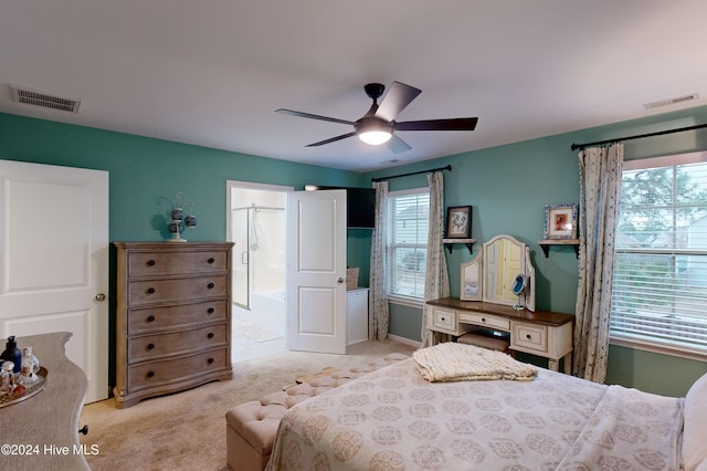 bedroom with ceiling fan, ensuite bathroom, and light colored carpet