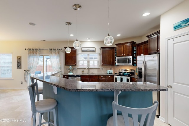 kitchen with pendant lighting, a kitchen island, sink, and appliances with stainless steel finishes