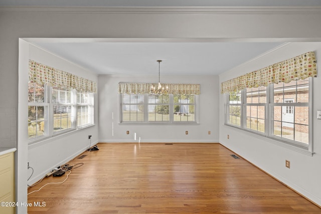 unfurnished dining area with light hardwood / wood-style floors, crown molding, and a chandelier