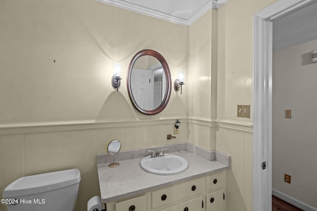 bathroom with vanity, crown molding, hardwood / wood-style flooring, toilet, and a textured ceiling