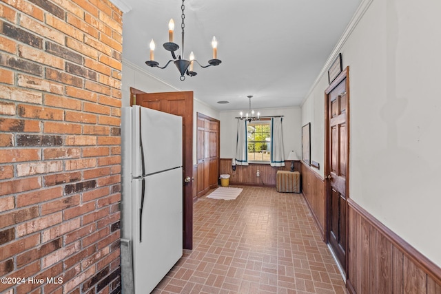 kitchen featuring wood walls, pendant lighting, white fridge, and a chandelier