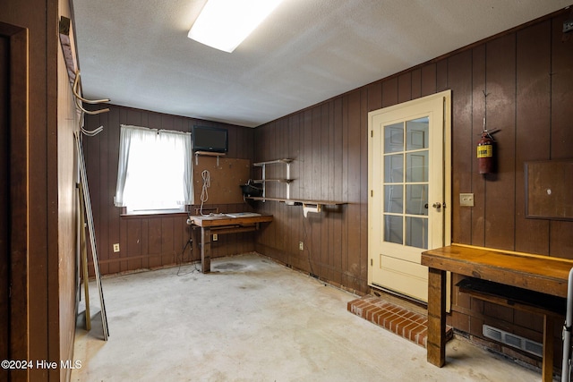 miscellaneous room with a workshop area, a textured ceiling, and wooden walls