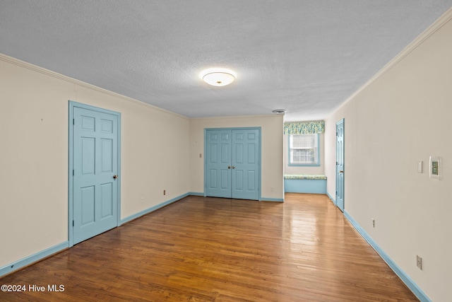 unfurnished bedroom featuring hardwood / wood-style flooring, ornamental molding, and a textured ceiling