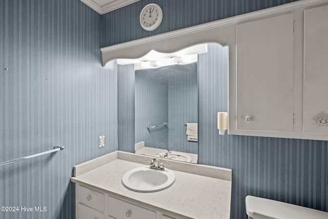 bathroom featuring toilet, vanity, and ornamental molding