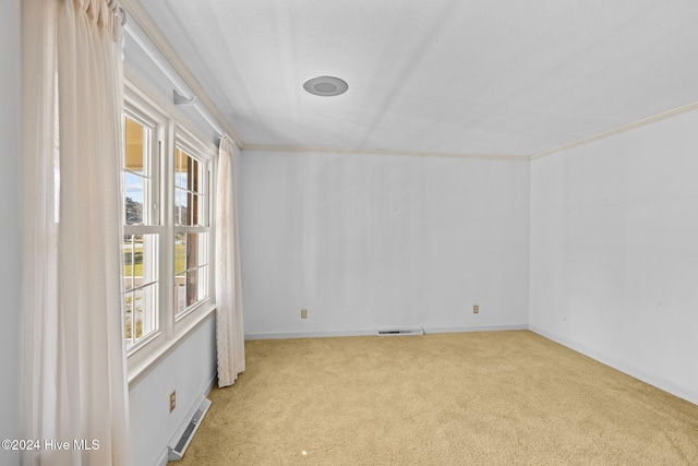 unfurnished room with a healthy amount of sunlight, ornamental molding, and light carpet