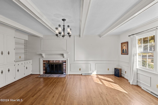 unfurnished living room featuring a textured ceiling, light hardwood / wood-style floors, a fireplace, and beamed ceiling