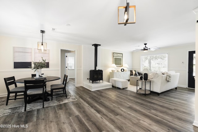 living room featuring ornamental molding, a wood stove, ceiling fan, and dark hardwood / wood-style flooring