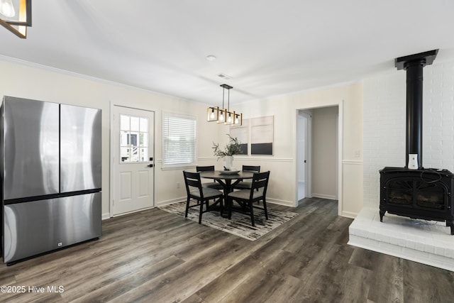 dining room with ornamental molding, dark hardwood / wood-style floors, and a wood stove