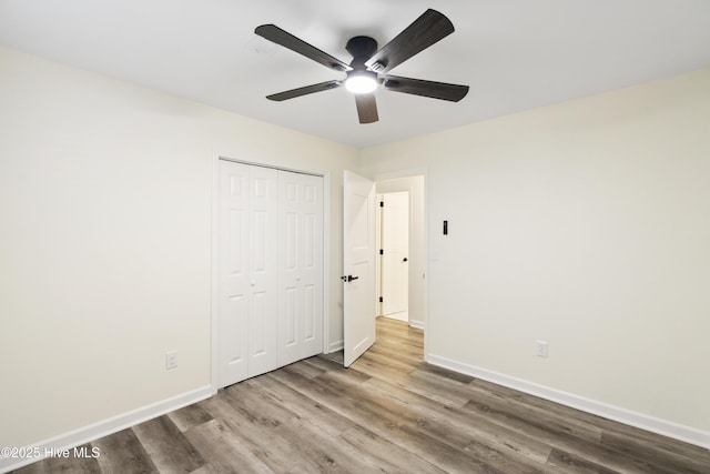 unfurnished bedroom with wood-type flooring, a closet, and ceiling fan