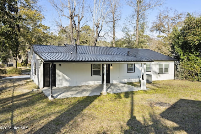 back of property with central AC, a lawn, and a patio area