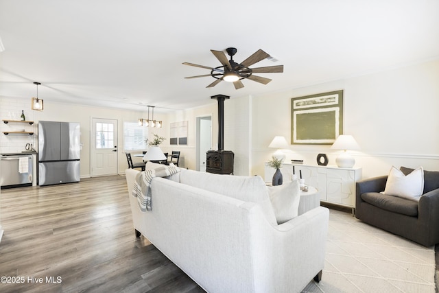 living room with a wood stove, ceiling fan, and light wood-type flooring