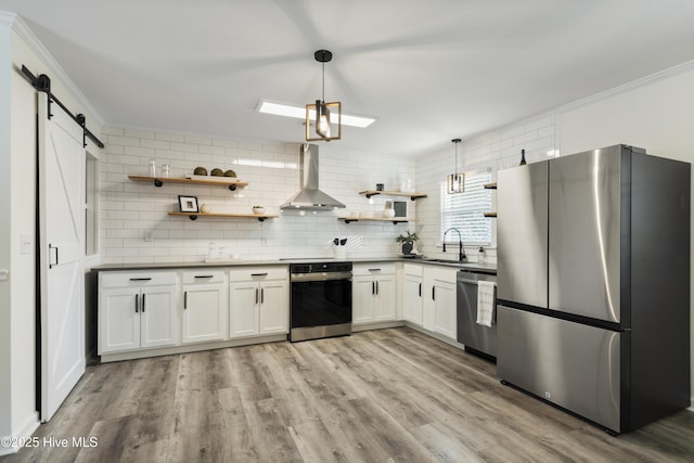 kitchen with white cabinetry, wall chimney range hood, hanging light fixtures, and appliances with stainless steel finishes