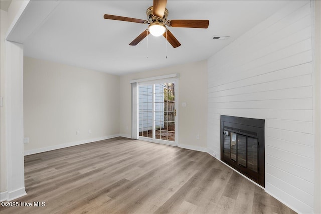 unfurnished living room with a fireplace, ceiling fan, and light wood-type flooring