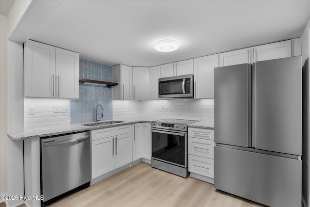 kitchen featuring white cabinetry, stainless steel appliances, sink, and light wood-type flooring