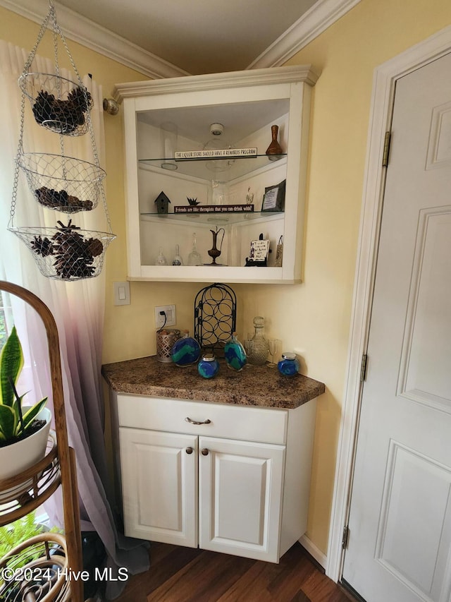 bar with dark wood-type flooring and crown molding