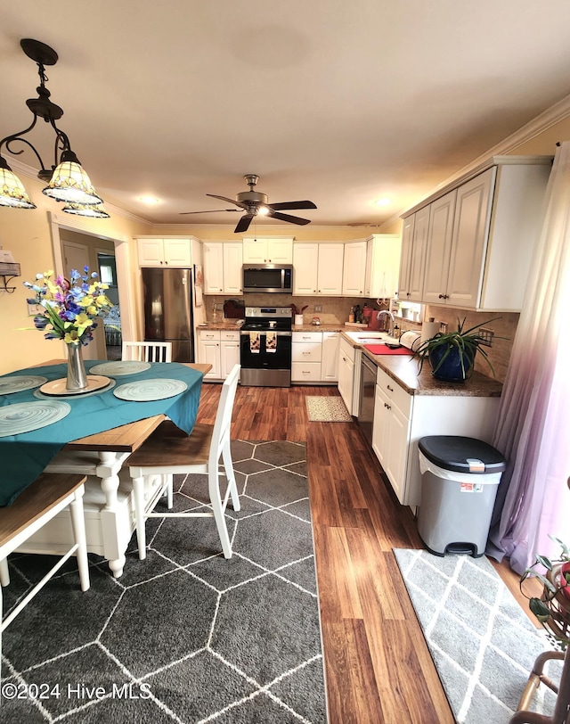 kitchen with dark wood-style floors, stainless steel appliances, a ceiling fan, decorative light fixtures, and white cabinetry