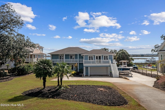 view of front of home with a garage, a water view, a balcony, and a front lawn