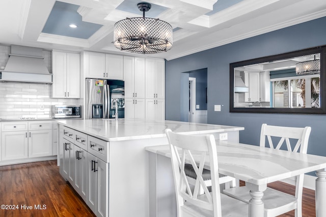 kitchen with appliances with stainless steel finishes, premium range hood, pendant lighting, dark hardwood / wood-style floors, and white cabinetry