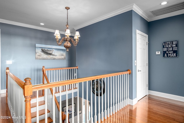 hallway featuring hardwood / wood-style flooring, ornamental molding, and a notable chandelier