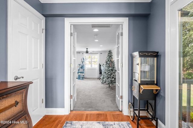 corridor featuring wood-type flooring and ornamental molding