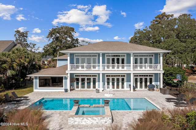 rear view of property with french doors, a patio, a balcony, and a swimming pool with hot tub