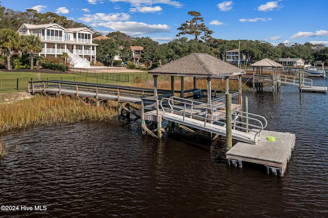 view of dock with a lawn and a water view