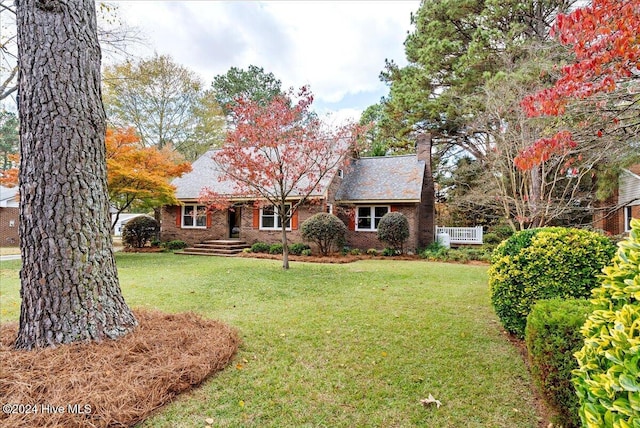 ranch-style house featuring brick siding, a chimney, and a front yard