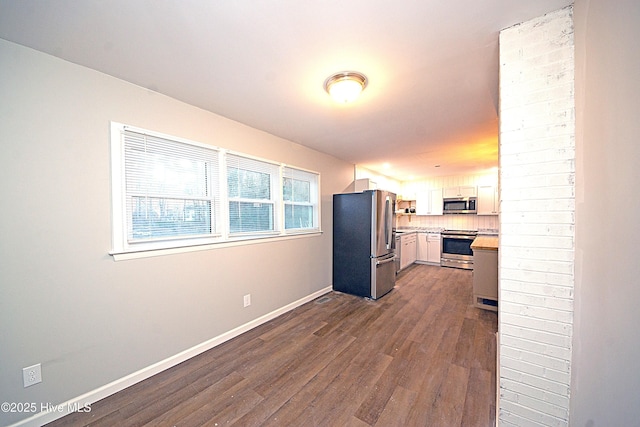 kitchen featuring appliances with stainless steel finishes, dark wood-type flooring, white cabinets, and decorative backsplash