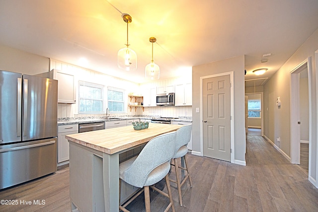 kitchen with stainless steel appliances, white cabinetry, a center island, and pendant lighting