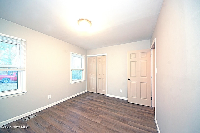 unfurnished bedroom with dark hardwood / wood-style flooring and a closet