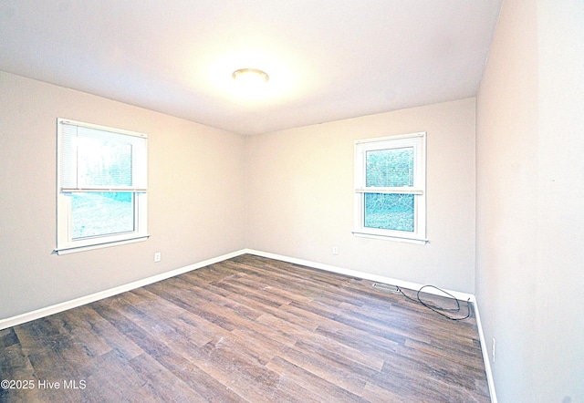 empty room with dark hardwood / wood-style floors and a wealth of natural light