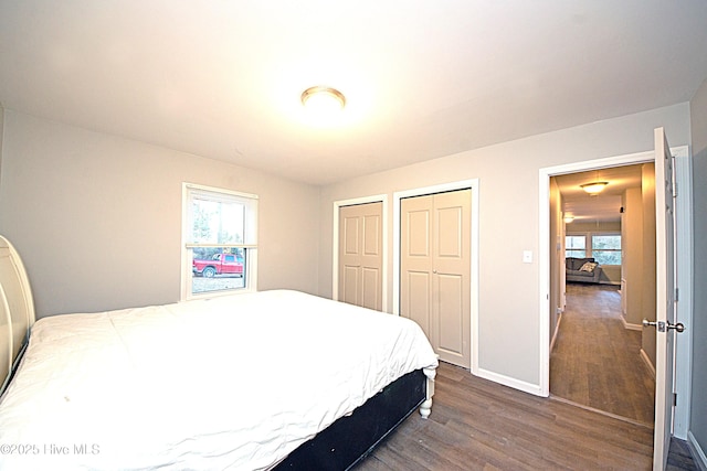 bedroom featuring multiple closets, dark hardwood / wood-style flooring, and multiple windows