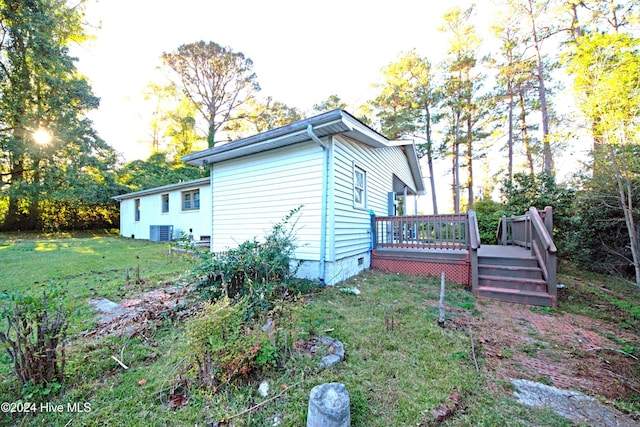 view of property exterior with cooling unit, a deck, and a lawn