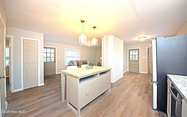 kitchen featuring stainless steel refrigerator, dark wood-type flooring, and hanging light fixtures