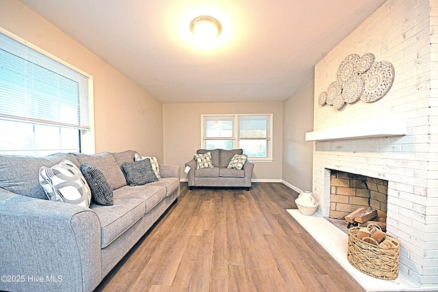 living room with a brick fireplace and hardwood / wood-style flooring