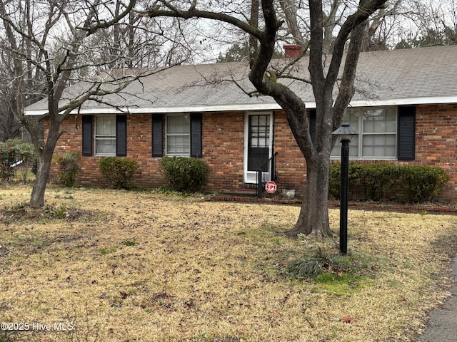 ranch-style house featuring brick siding and roof with shingles