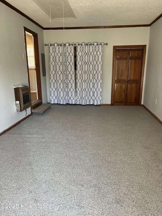 spare room featuring heating unit, a textured ceiling, attic access, and crown molding