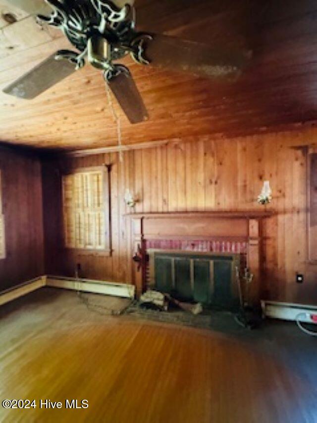 interior details with wood-type flooring, wooden walls, baseboard heating, a fireplace, and wood ceiling