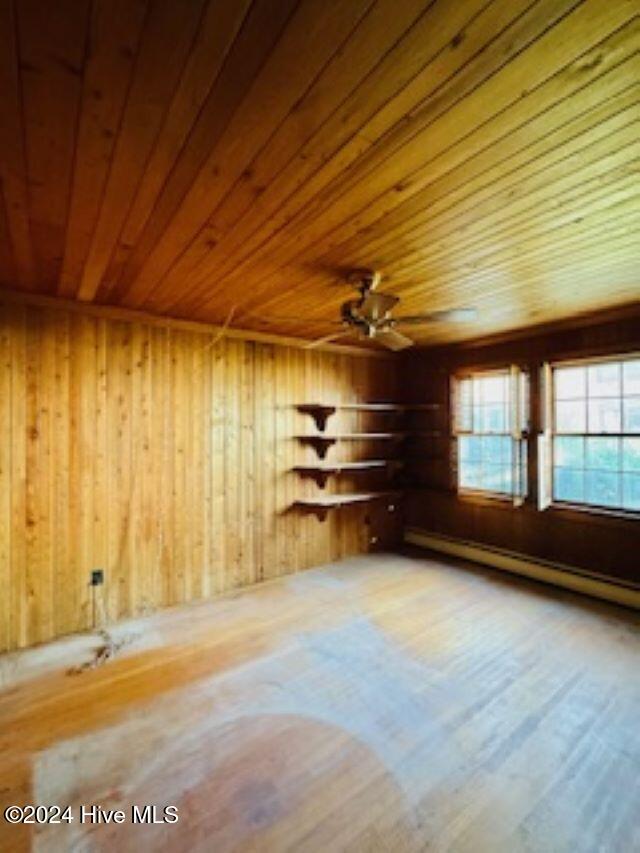 interior space featuring ceiling fan, baseboard heating, wood walls, hardwood / wood-style floors, and wood ceiling