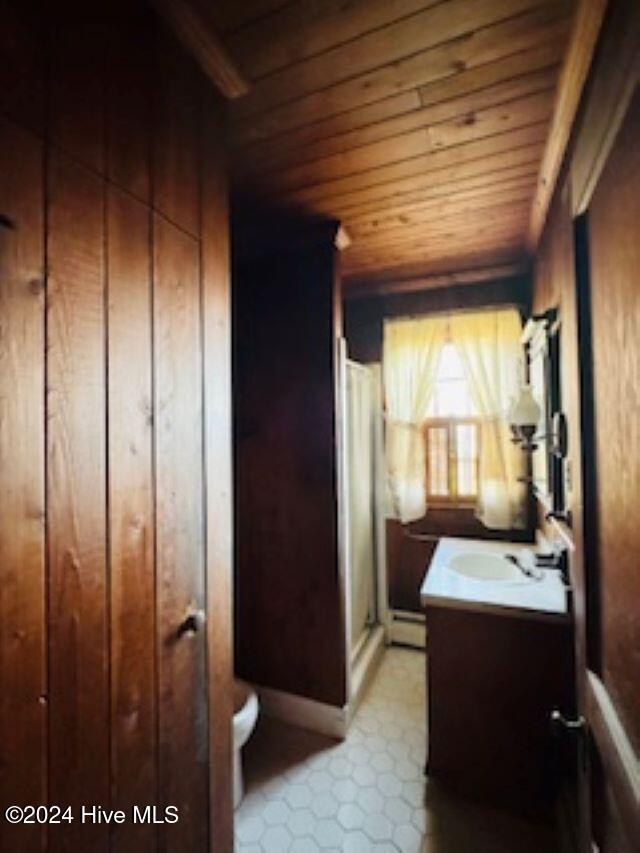 bathroom with wooden ceiling, a baseboard heating unit, wooden walls, vanity, and a shower with shower door