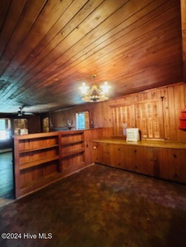 bonus room with wooden ceiling and wood walls