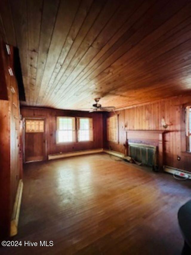 100 Riverview Ave, Camden, NC 27921 - unfurnished living room with wood ceiling, a baseboard radiator, wood finished floors, wooden walls, and a ceiling fan