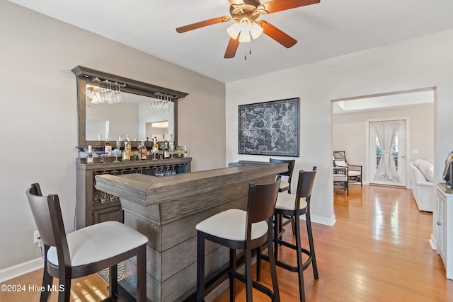 bar featuring ceiling fan, hanging light fixtures, white cabinets, and light hardwood / wood-style floors