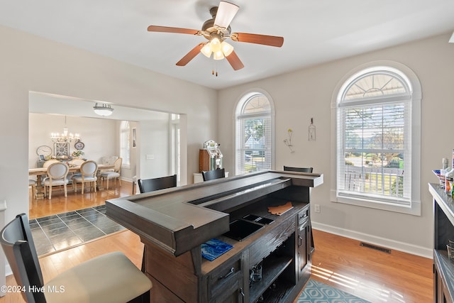 rec room with hardwood / wood-style floors and ceiling fan with notable chandelier