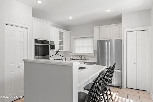 kitchen with white cabinetry, sink, stainless steel appliances, a breakfast bar, and light tile patterned floors