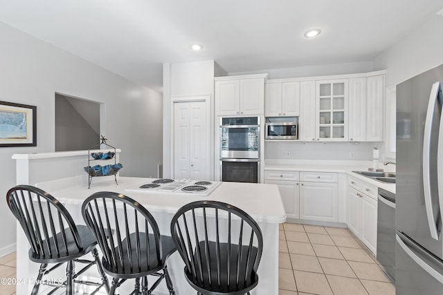 kitchen with stainless steel appliances, light tile patterned floors, a center island, white cabinetry, and a breakfast bar area