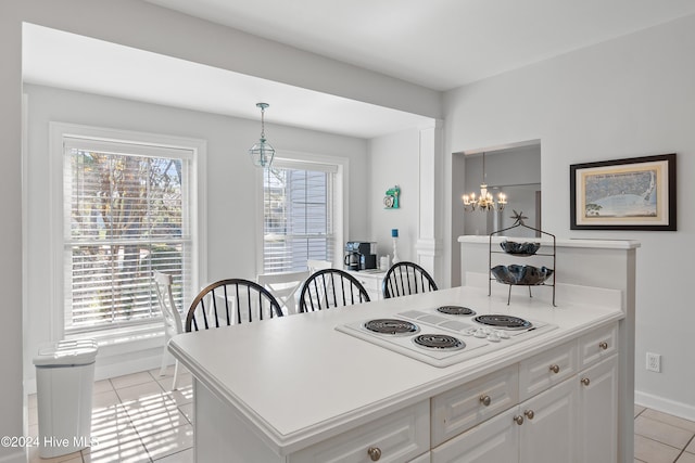 kitchen featuring white cabinets, hanging light fixtures, white electric stovetop, light tile patterned floors, and a notable chandelier